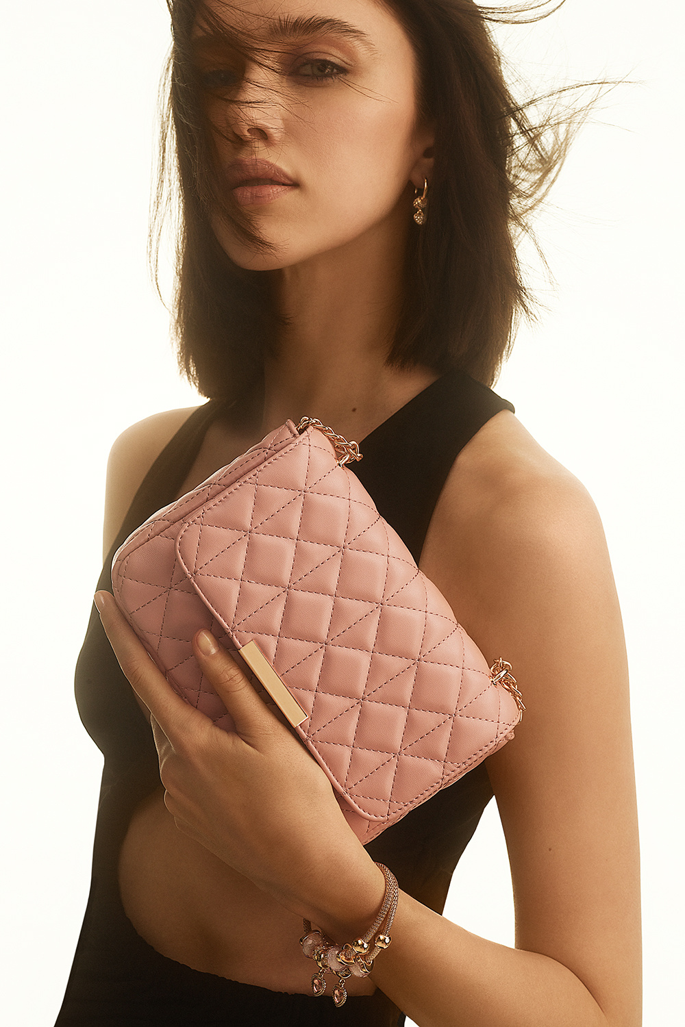 Lyserød taske med quiltet design og guldfarvet skulderrem