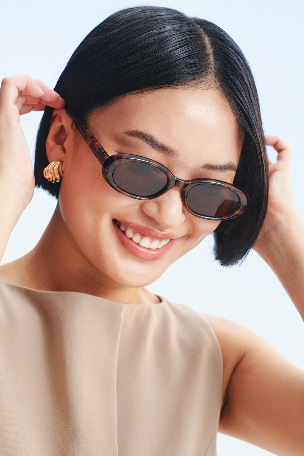 Guldfarvede øreringe i bølget dråbeform