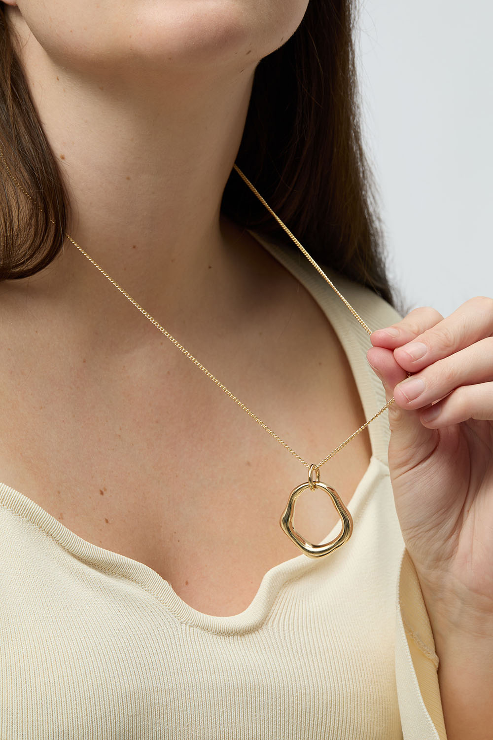 Guldfarvet halskæde med rundt vedhæng i organisk form